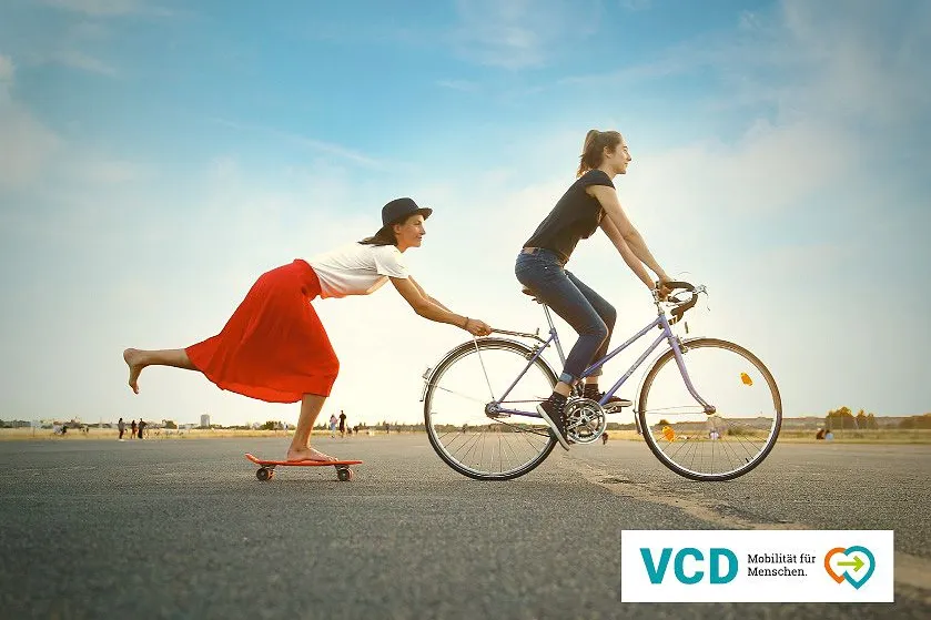 Zwei Frauen auf Fahrrad und Skateboard
